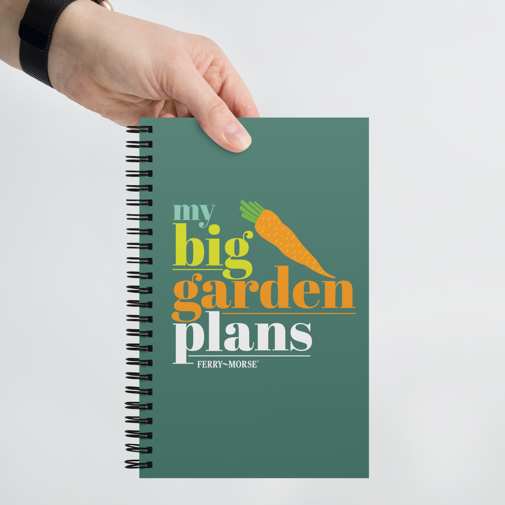 A green spiral-bound notebook with the title 'my big garden plans' printed on the cover, alongside an illustration of a carrot.